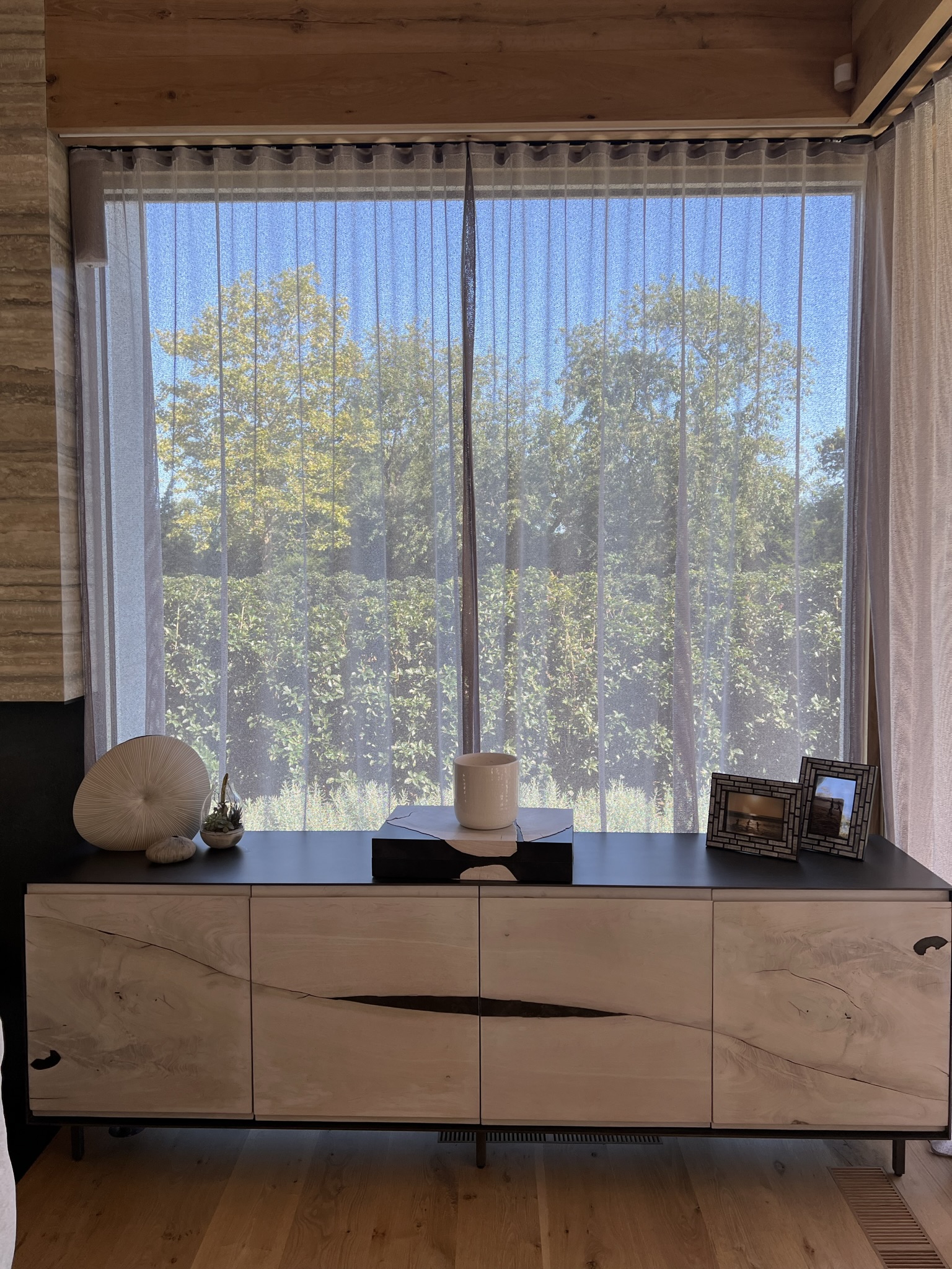 Tailored sheer drapery integrated into a warm wood-lined residential window